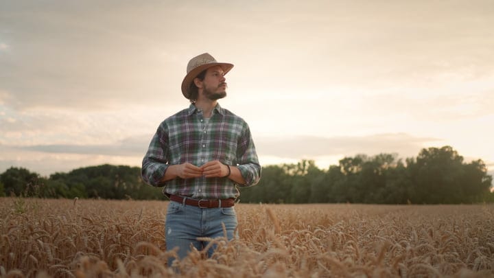 Thoughtful Farmer in Wheat Field at Sunset