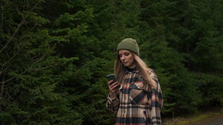 Young Woman Navigates Wilderness With Smartphone in Hand