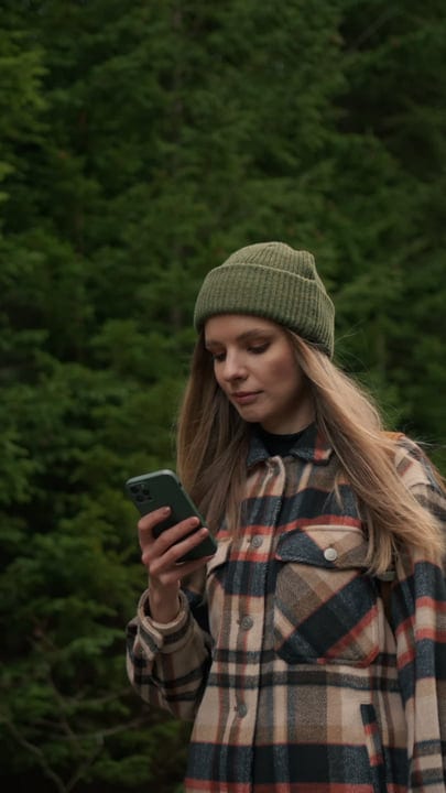 Young Woman Navigates the Wilderness With Her Smartphone