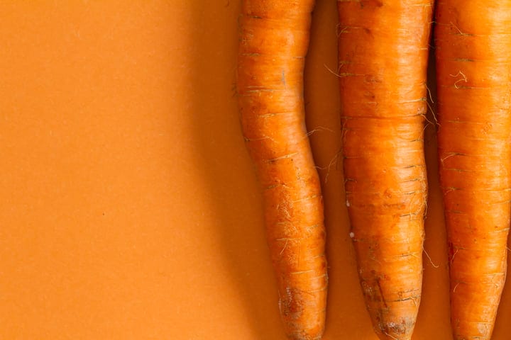 Vibrant Fresh Carrots Against a Bold Orange Canvas