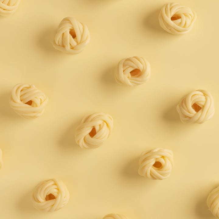 Rows Of Pasta Knots Against A Soft Yellow Backdrop