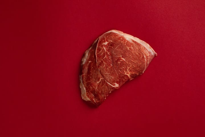 A Single Cut of Beef on a Bold Red Background
