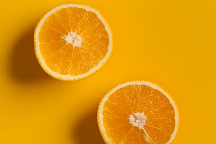 Sliced Orange Halves on Vibrant Yellow Background
