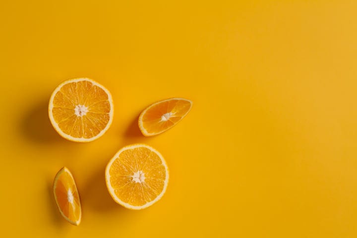 Vibrant Oranges Sliced On Sunny Yellow Background