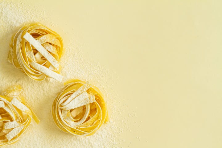 Golden Pasta Nestled in Flour on Yellow Surface