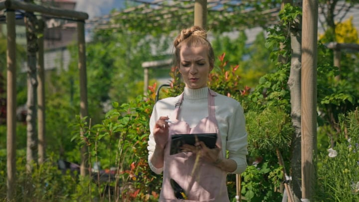 Focused Gardener Takes Notes In Vibrant Greenhouse