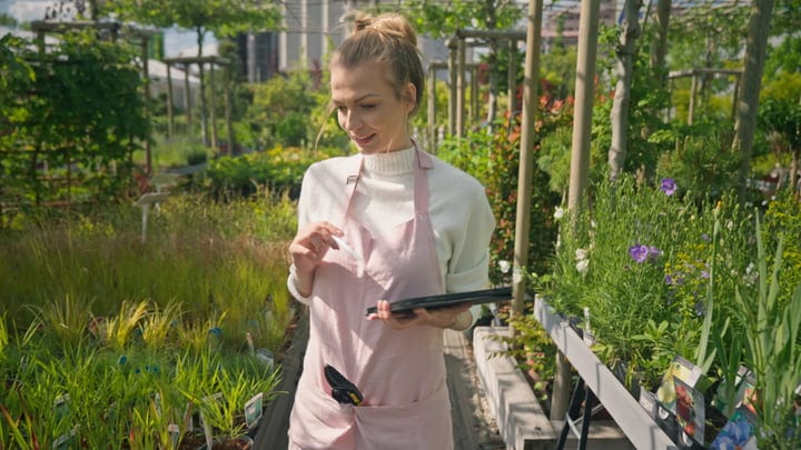 Gardener Tends to Lush Greenhouse Oasis in Spring