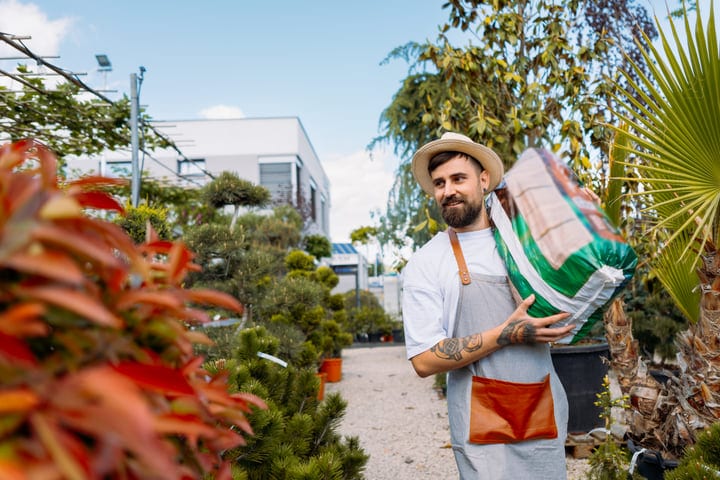 Joyful Gardener Carries Supplies Through Lush Greenhouse