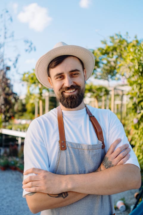Smiling Gardener Embraces New Growth In Greenhouse Sunshine