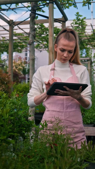 Focused Gardener Taking Notes In Lush Greenhouse
