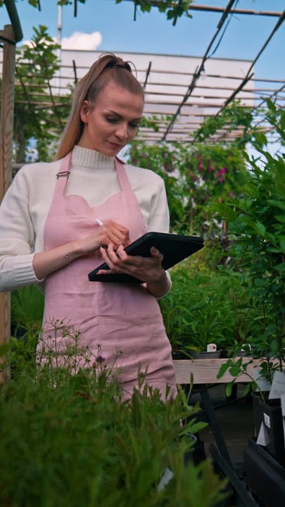 Thoughtful Gardener Using Tablet in Lush Greenhouse