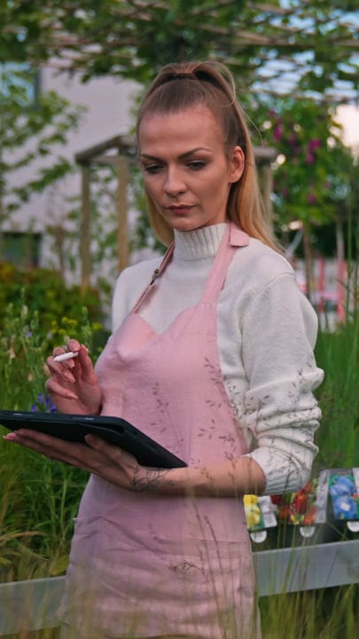 Focused Gardener Uses Tablet In Lush Greenhouse