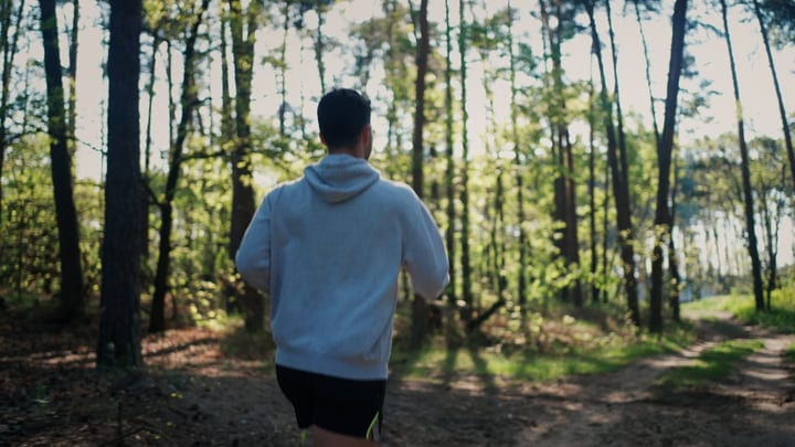Man Jogging Through Sunlit Forest Pathway