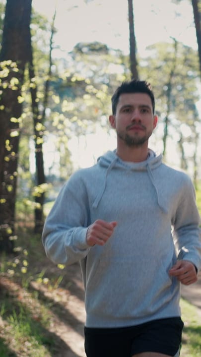 Young Man Running Through Sunny Forest Path On A Bright Morning