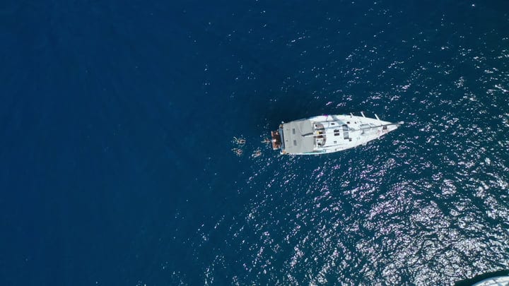 Sailboat Glides Over Sparkling Turquoise Waters With Swimmers