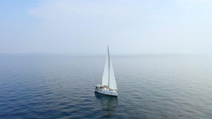 Sailboat Glides Peacefully Across Turquoise Waters Under Clear Skies