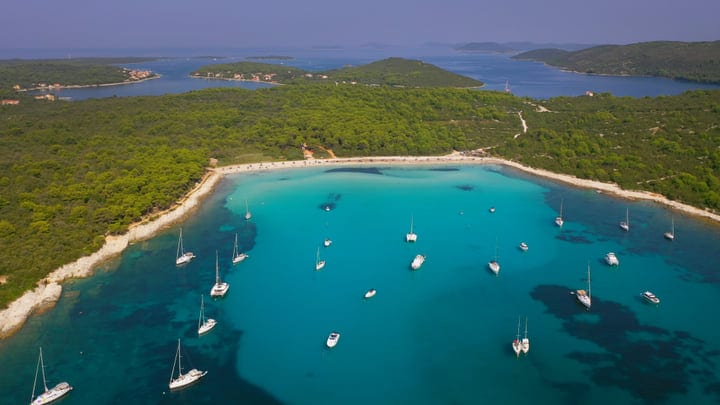 Sailboats Anchored In Serene Turquoise Bay Under Blue Skies
