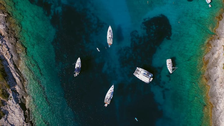 Sailboats Drift Over Turquoise Waters In Idyllic Bay