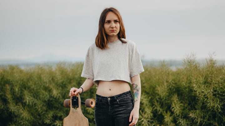 Young Woman with Skateboard on Scenic Country Road