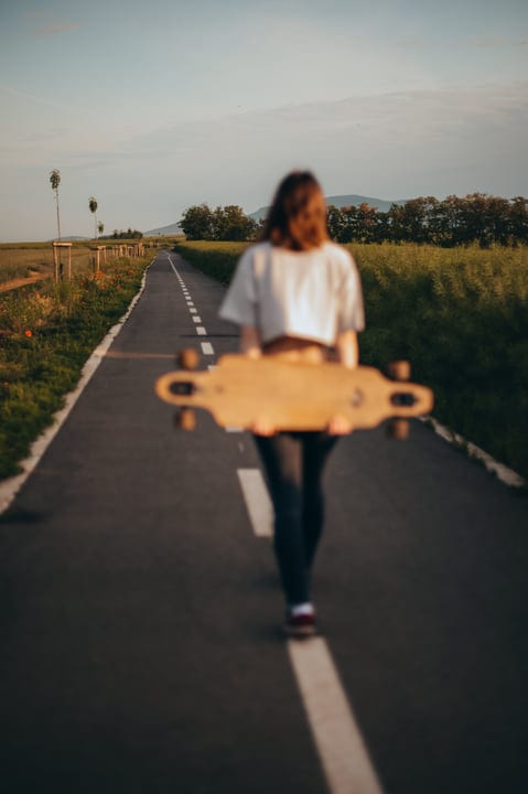 Sunlit Journey With Skateboard On A Country Road