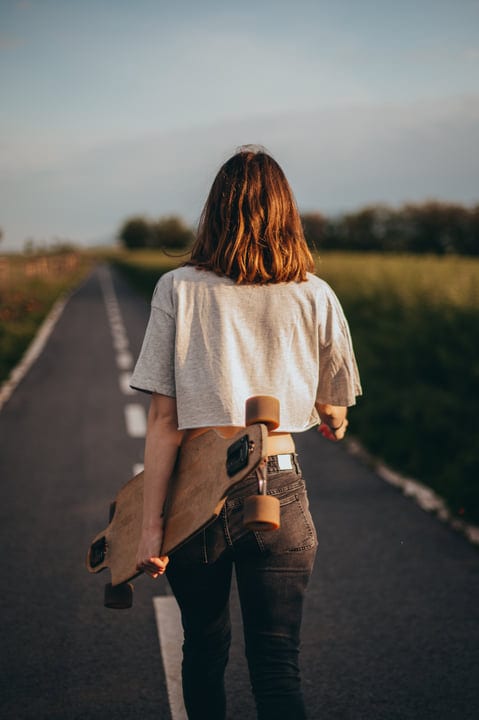 Young Skateboarder Strolls Down Serene Country Road