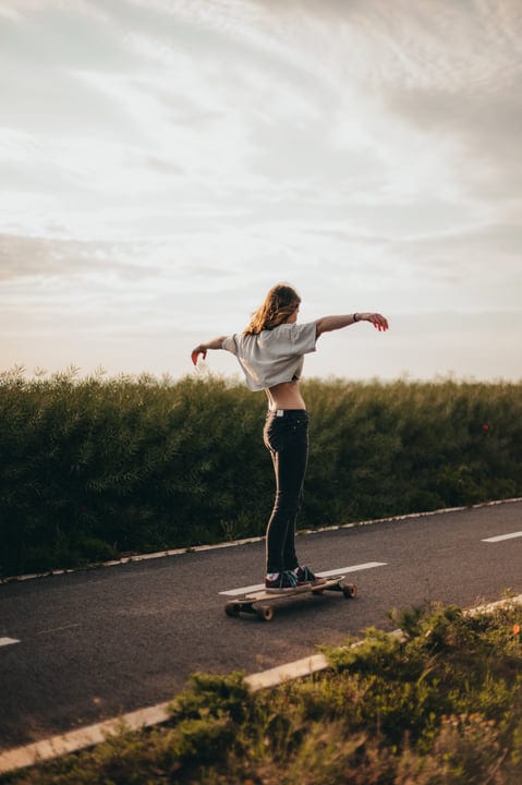 Skateboarder Glides Effortlessly Down A Country Road At Sunset