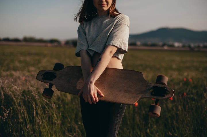 Young Woman Embraces Her Skateboard On Scenic Road
