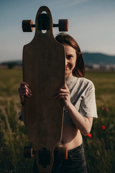 A Youthful Spirit Hides Behind A Skateboard In Nature