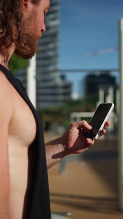 Skater Checks Smartphone Under The Urban Sunset Sky
