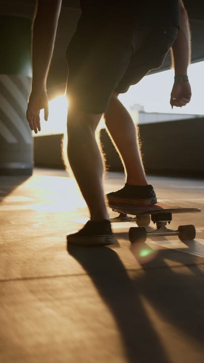 Skateboarder Glides Through Sunlit Urban Landscape