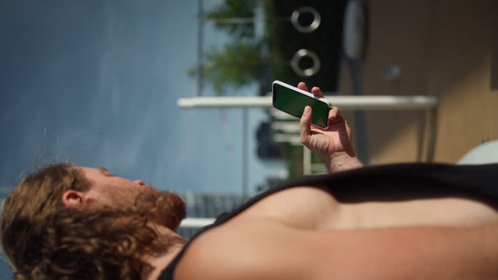 Young Skater Relaxing With Smartphone At Sunset