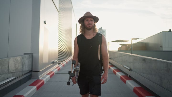Skater Walks Confidently Into The Urban Sunset Glow