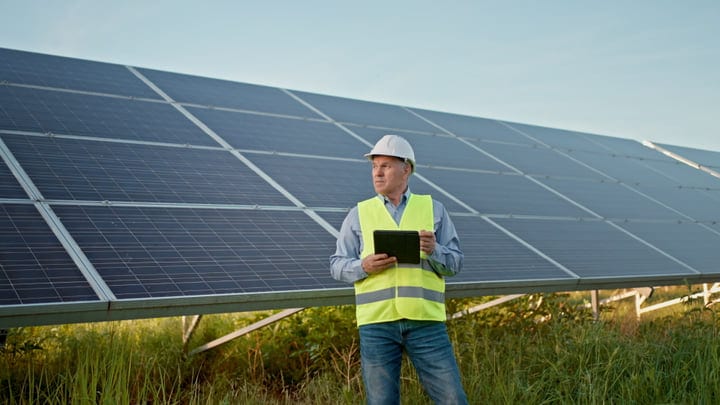 Engineer Surveys Solar Panels Under A Clear Sky
