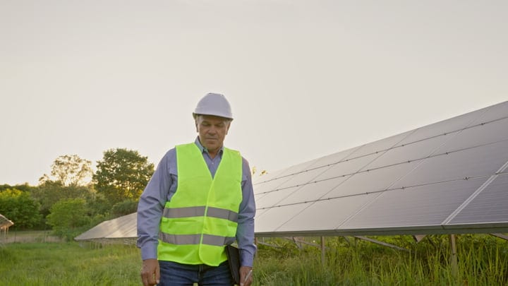 Solar Engineer Evaluates Panels Amidst Sunlit Fields