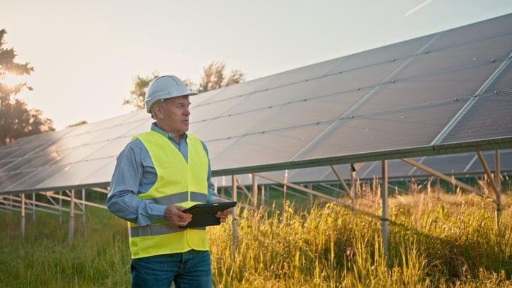 An Engineer Surveys Solar Panels at Sunrise