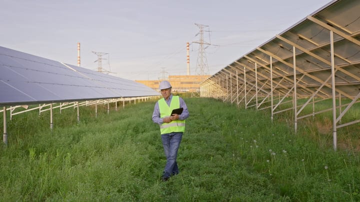 Solar Engineer Conducts Inspection Amidst Rows Of Panels