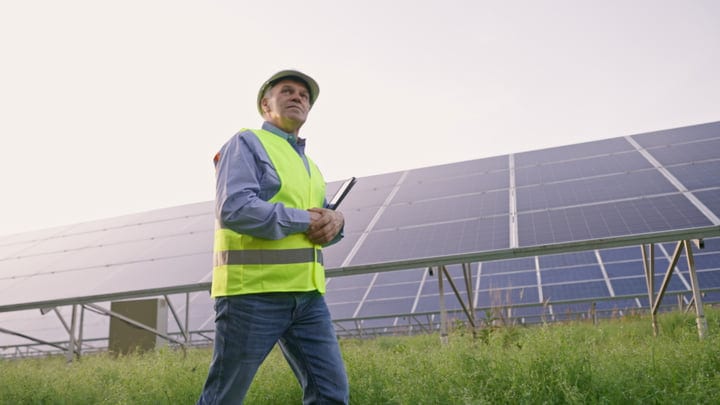 Focused Engineer Surveys Solar Panels at Sunrise