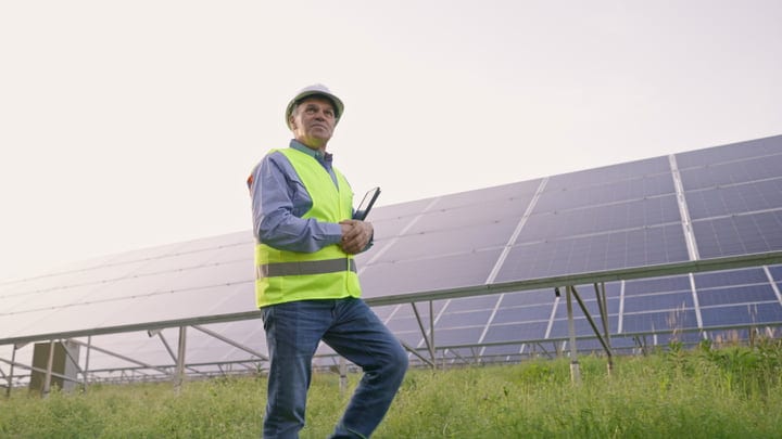 Engineer Surveys Solar Panels Under A Clear Sky