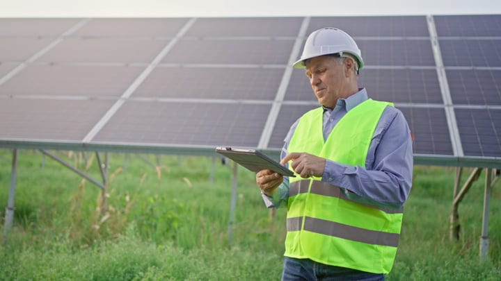 Focused Engineer Conducts Solar Panel Inspection With Tablet
