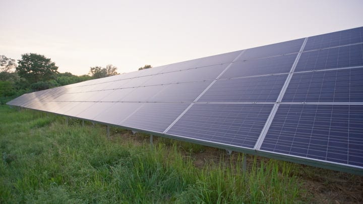 Sunrise Illuminates Solar Panels In A Verdant Landscape
