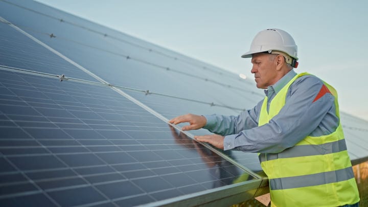 Dedicated Engineer Inspects Solar Panels Under Clear Skies