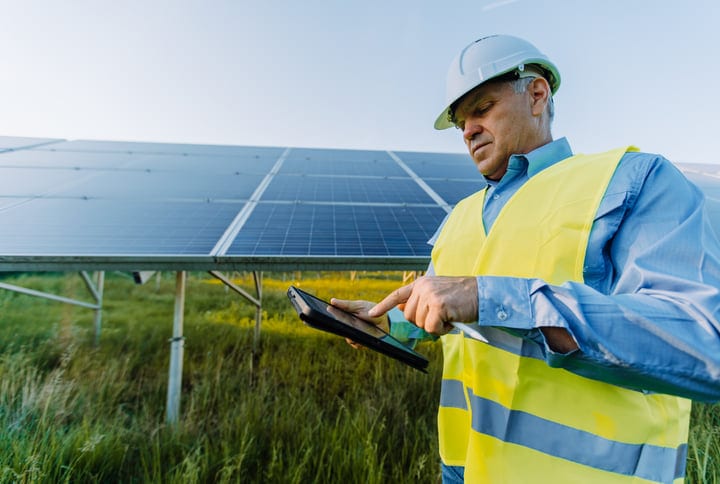 Solar Engineer Conducts Inspection Under Bright Sky