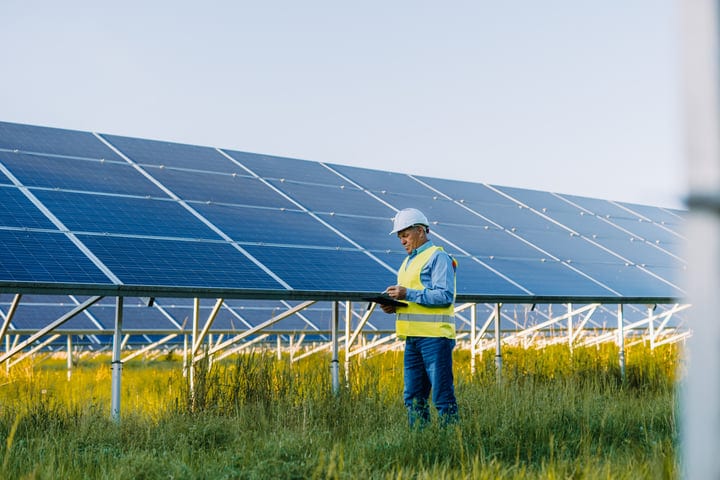 Engineer Examines Solar Panels Under Clear Sky
