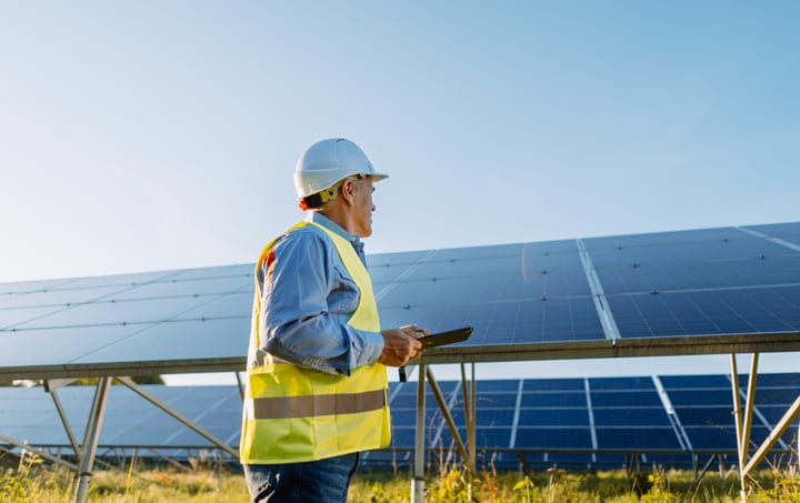 Engineer Surveys Solar Panels Under Clear Blue Skies