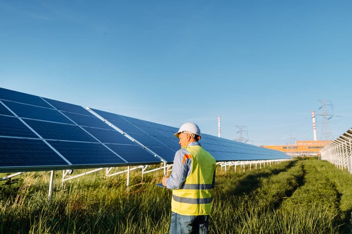 Solar Engineer Inspects Panels Under Clear Blue Sky