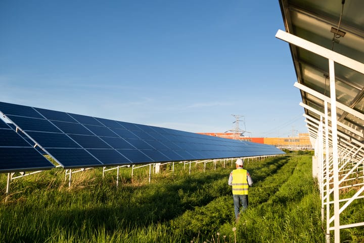 Engineer Inspects Solar Panels Under Clear Blue Skies