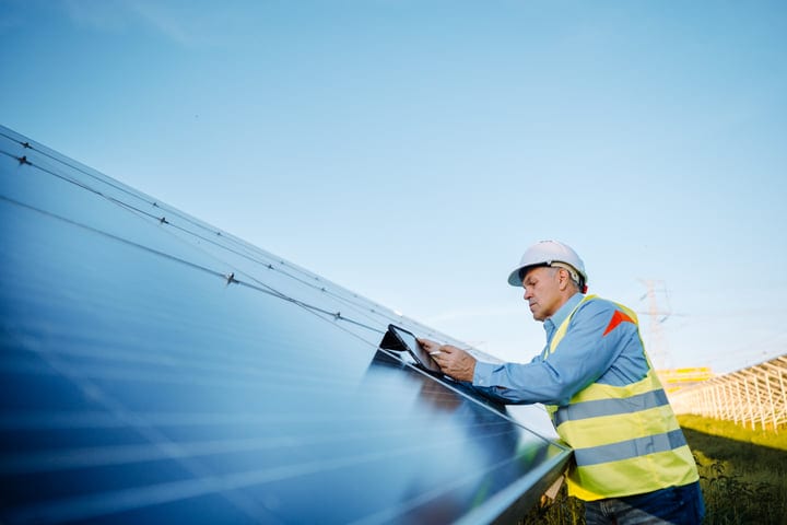 Dedicated Engineer Examines Solar Panels Under Clear Skies