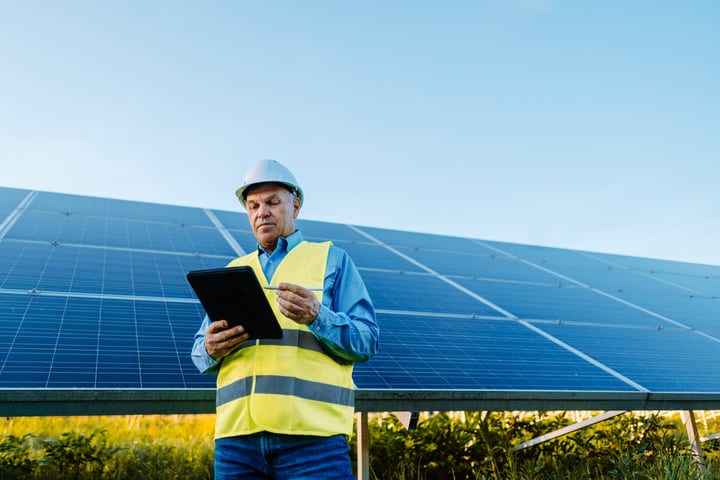 Engineer Evaluates Solar Panels Under Clear Blue Skies