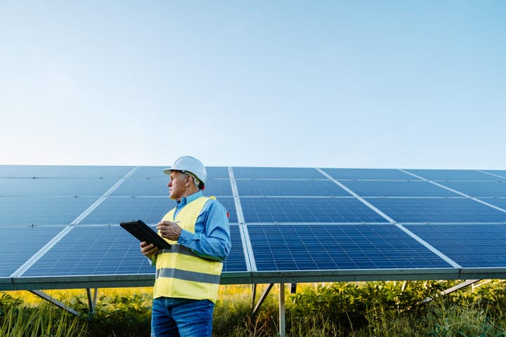 Engineer Examining Solar Panels Under Clear Skies
