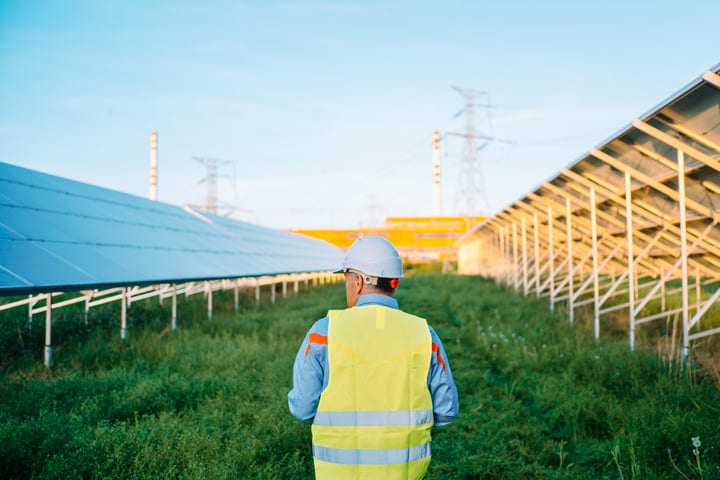 Engineer Inspects Solar Panels Under Clear Blue Sky